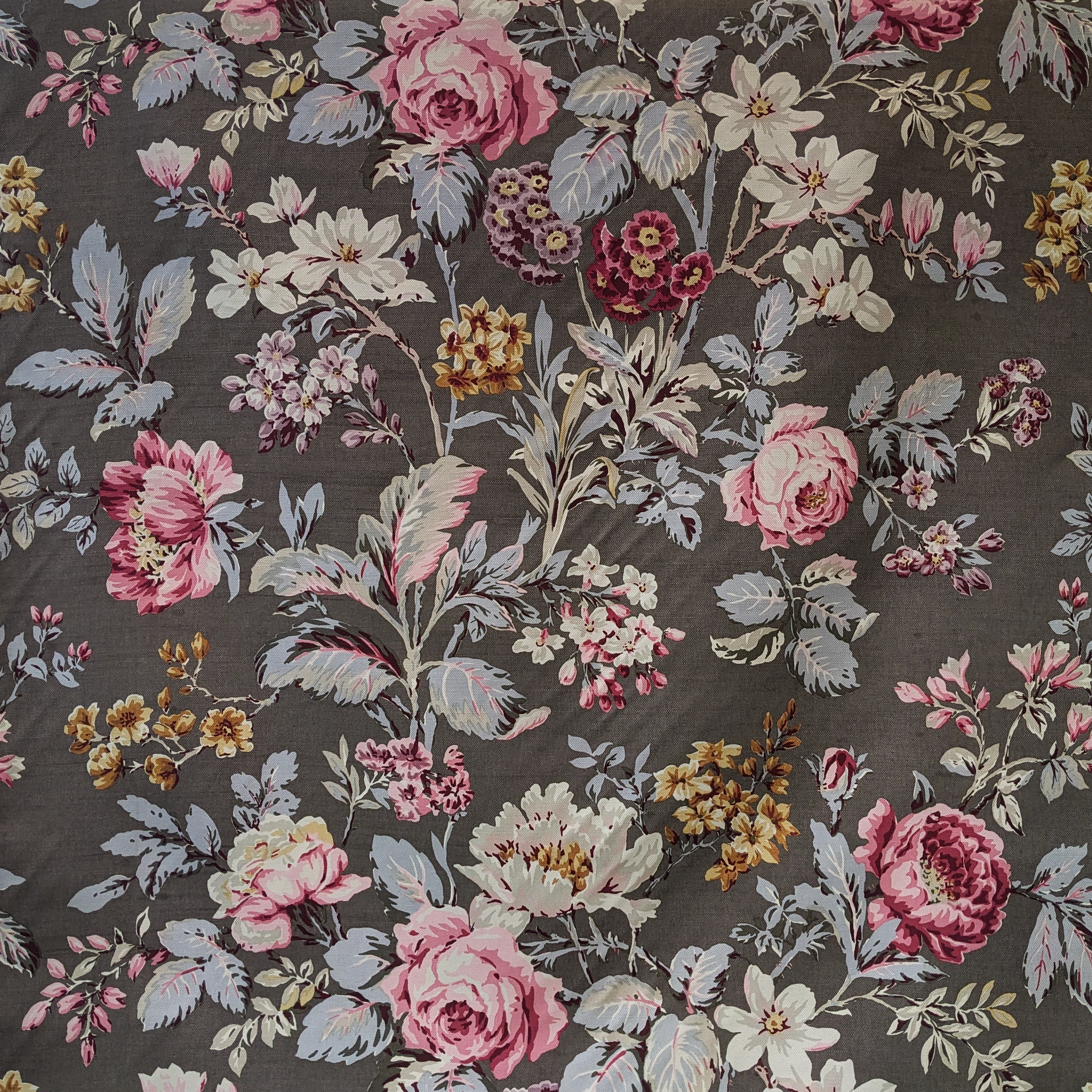 Floral patterned fabric with pink, white, and yellow flowers on a dark background