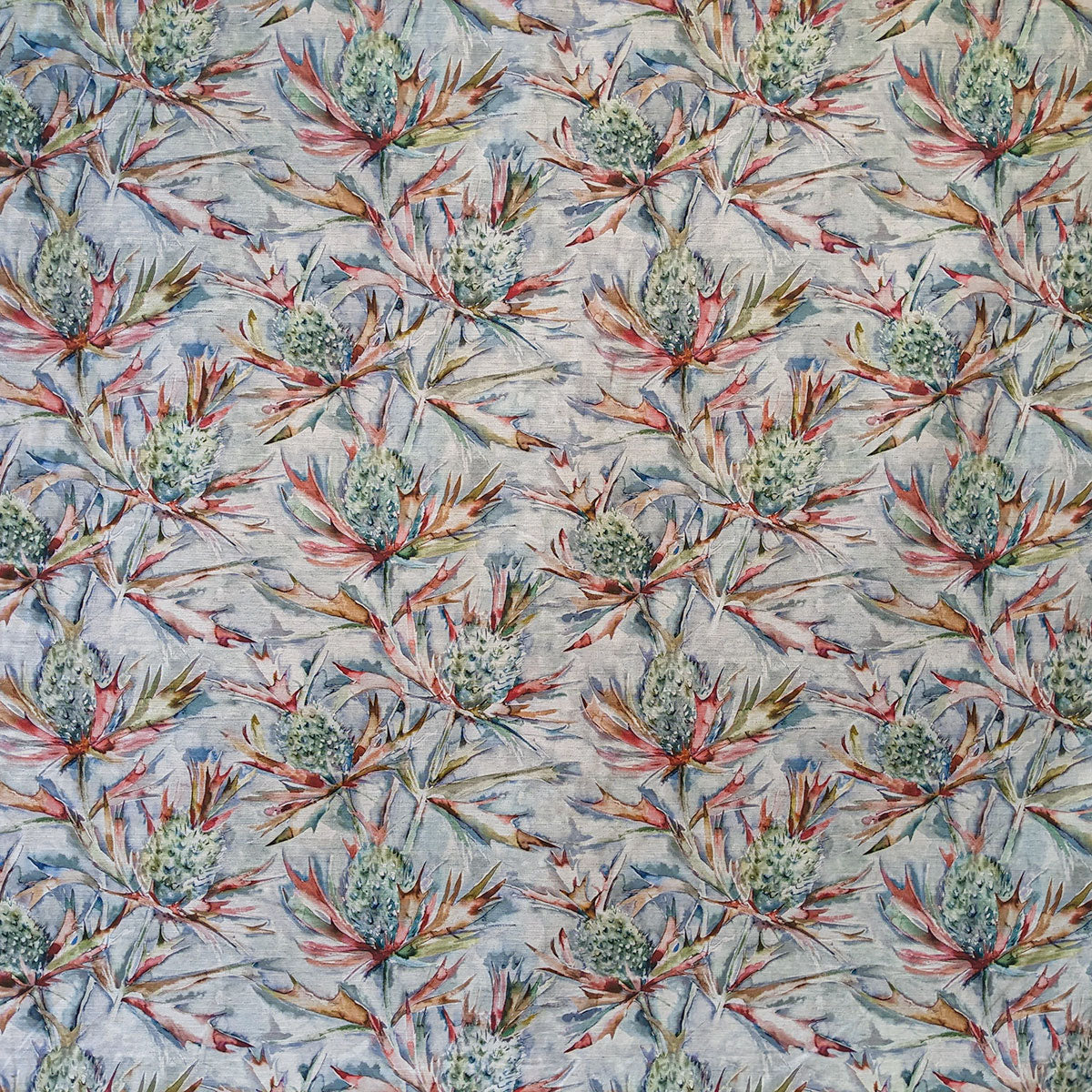 Thistle-patterned fabric with red and green leaves on a light blue background