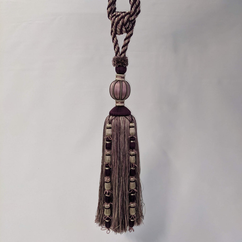 Decorative tassel with braided rope and beads on a white background