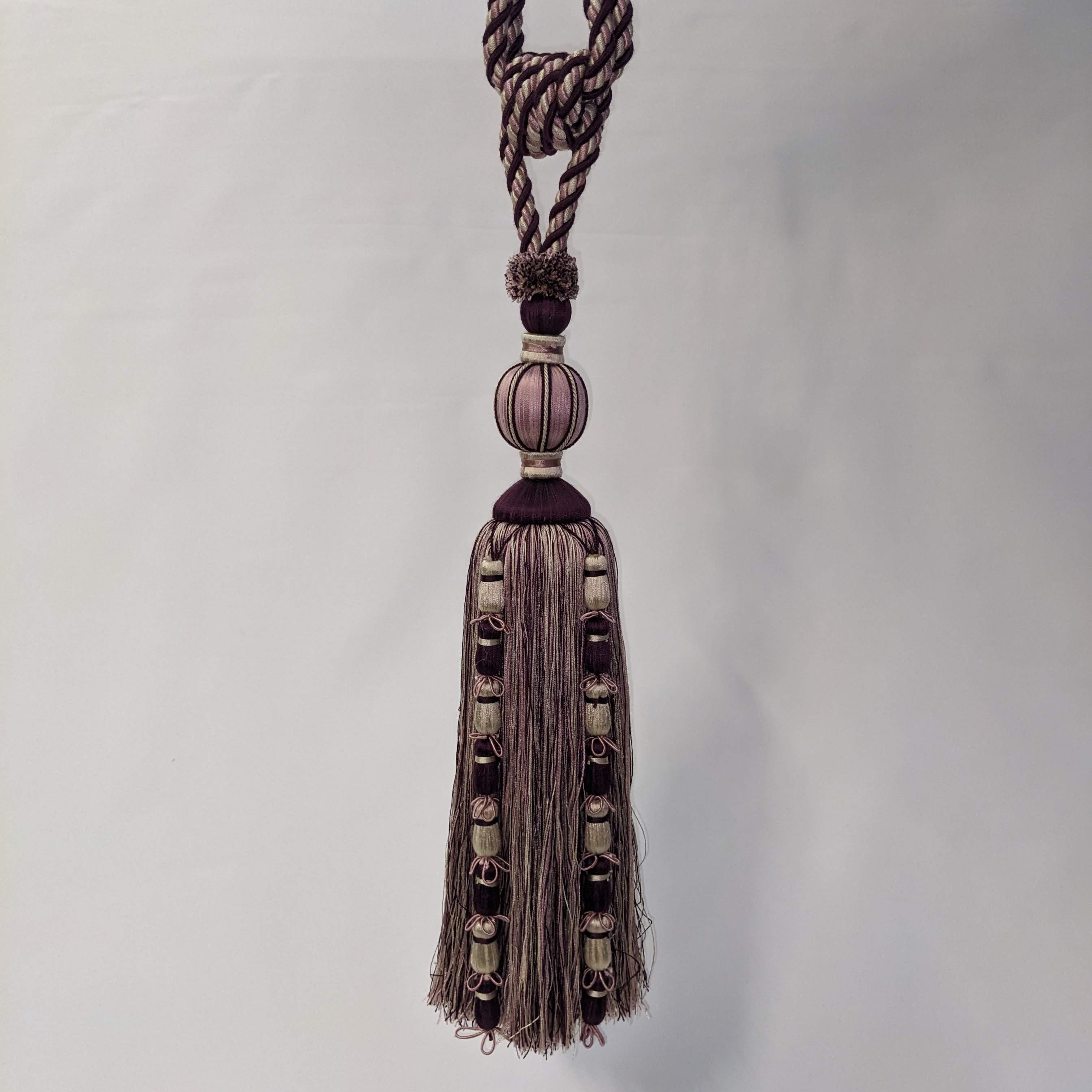 Decorative tassel with braided rope and beads on a white background