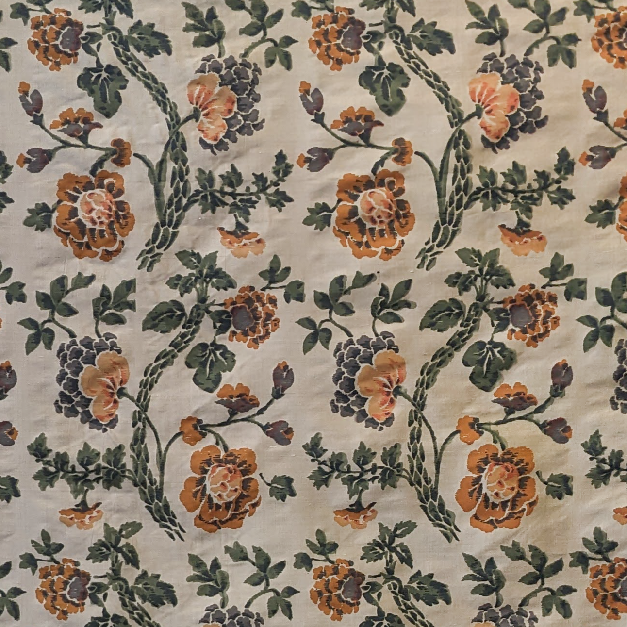 Floral patterned fabric with orange flowers and green leaves on a beige background