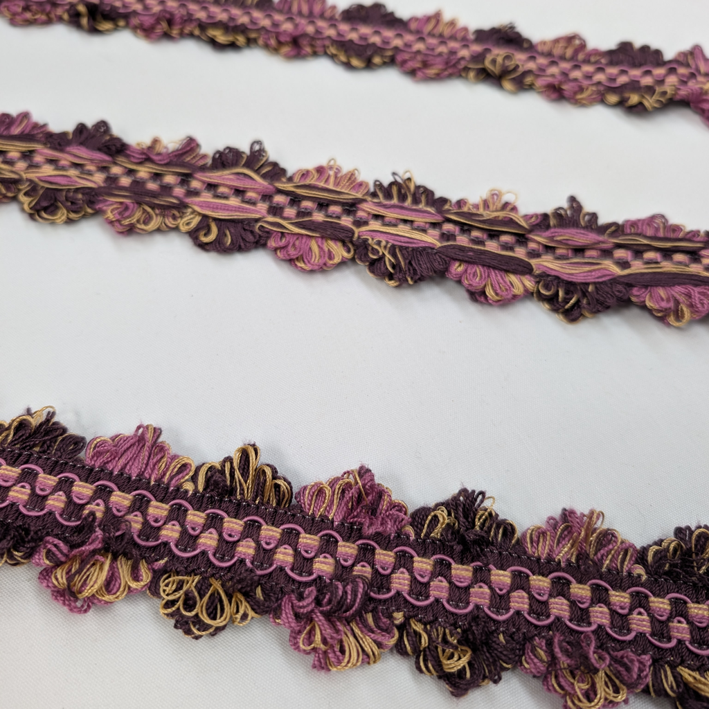 Decorative lace trim in purple and gold on a white background
