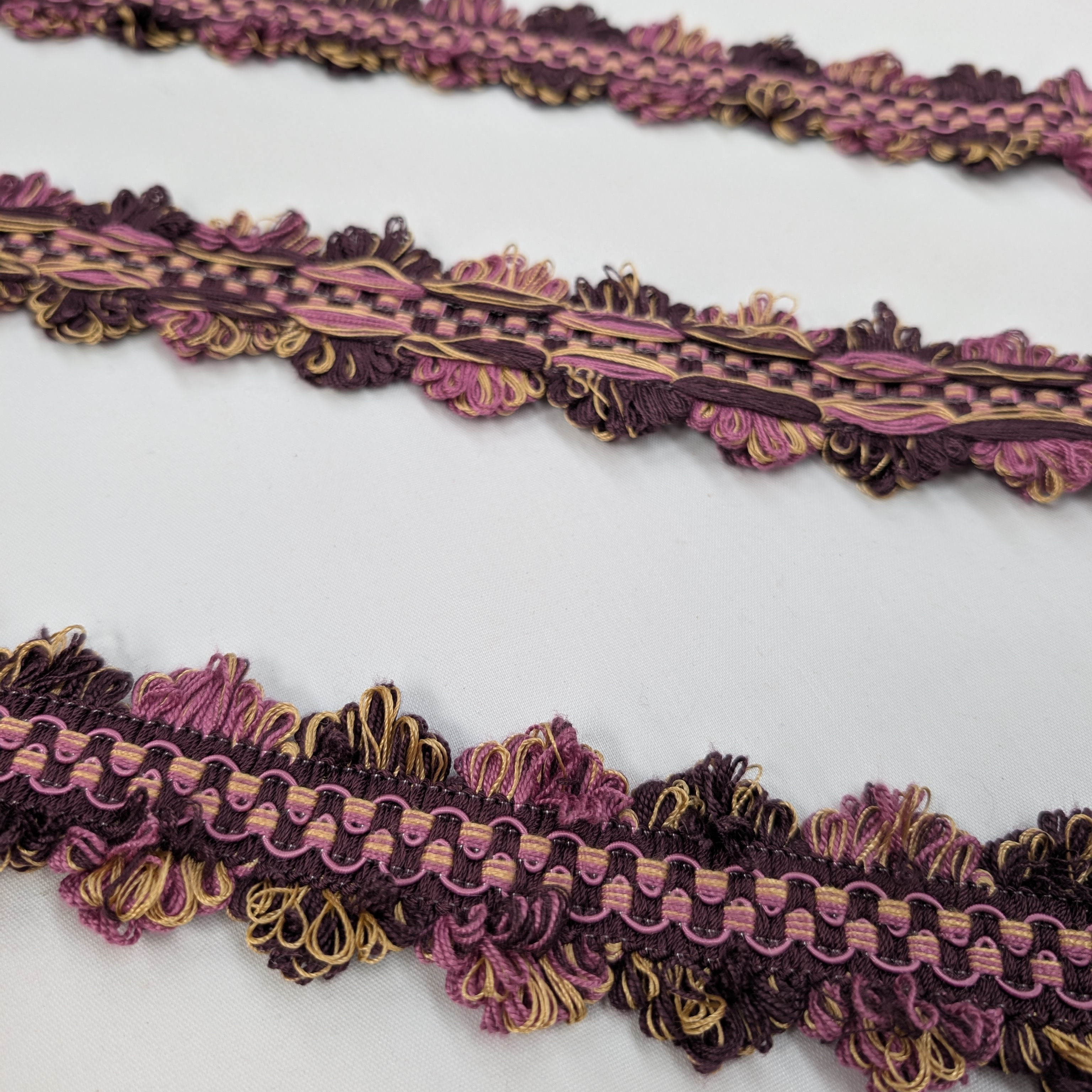 Decorative lace trim in purple and gold on a white background