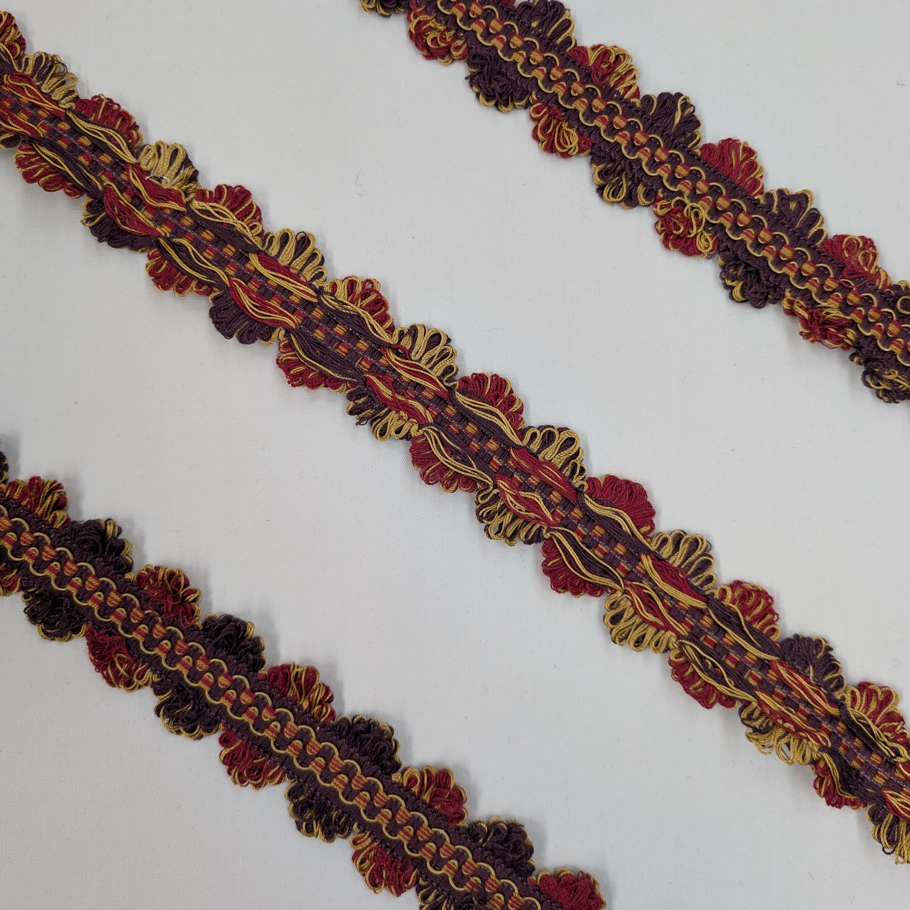 Decorative trim with red, gold, and brown colors on a white background