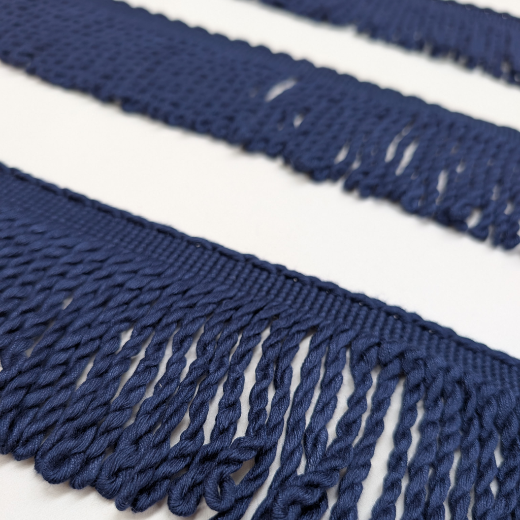 Close-up of blue fabric fringe on a white background