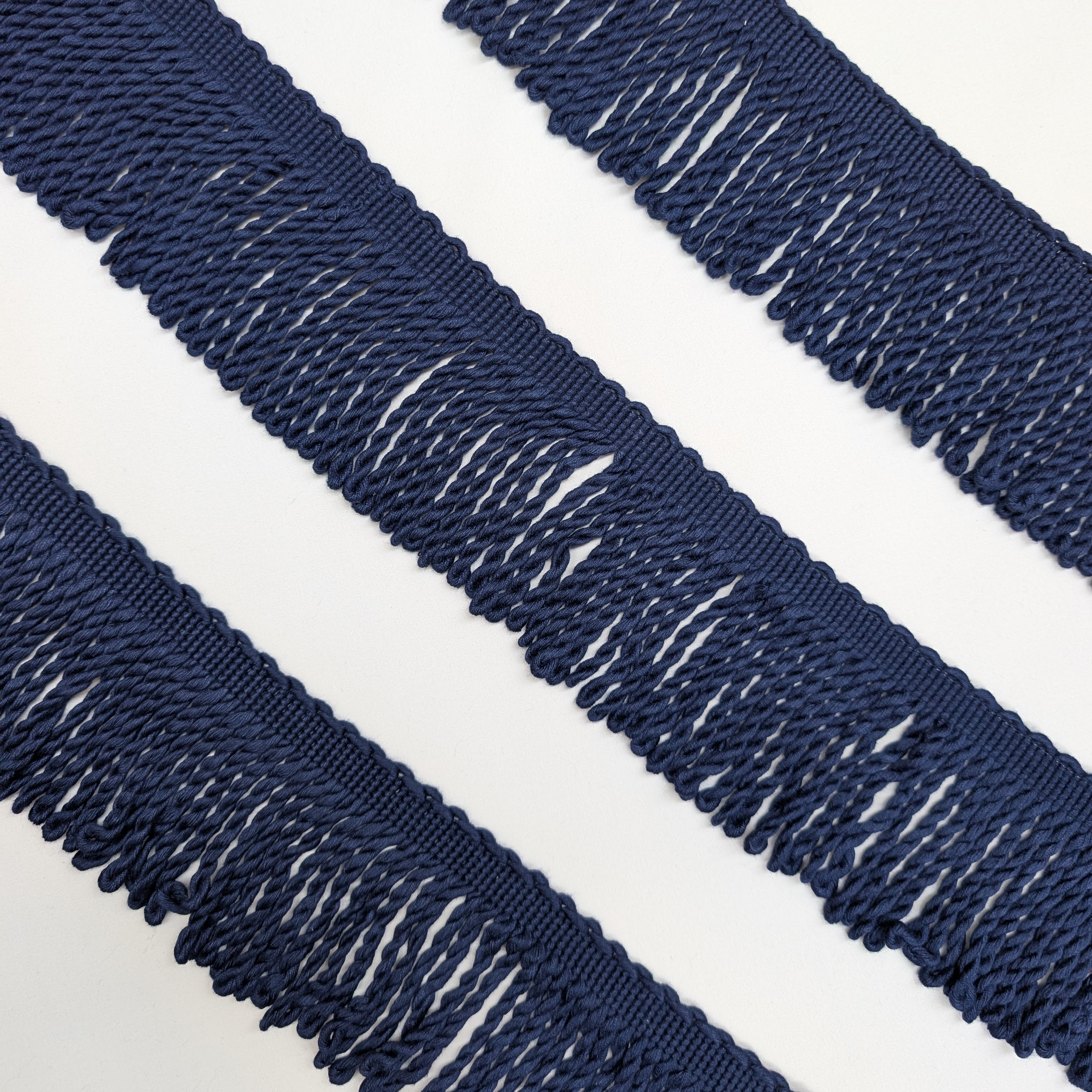 Navy blue fringed fabric trim on a white background