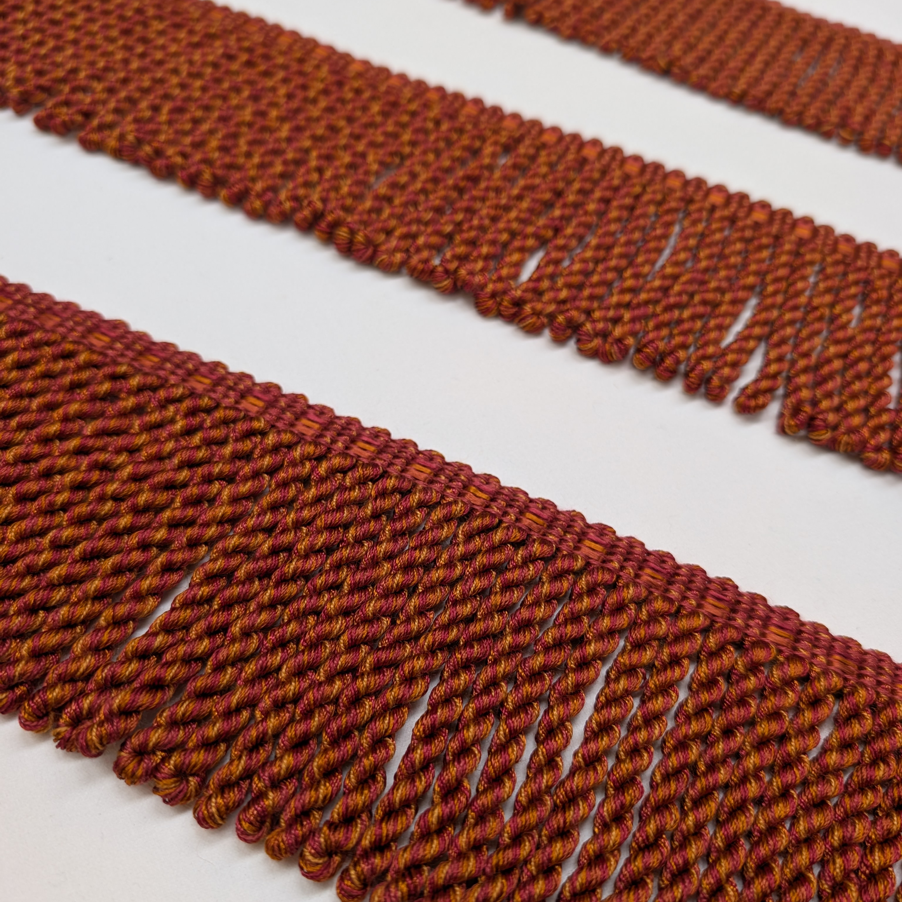 Close-up of red and orange braided trim on a white background