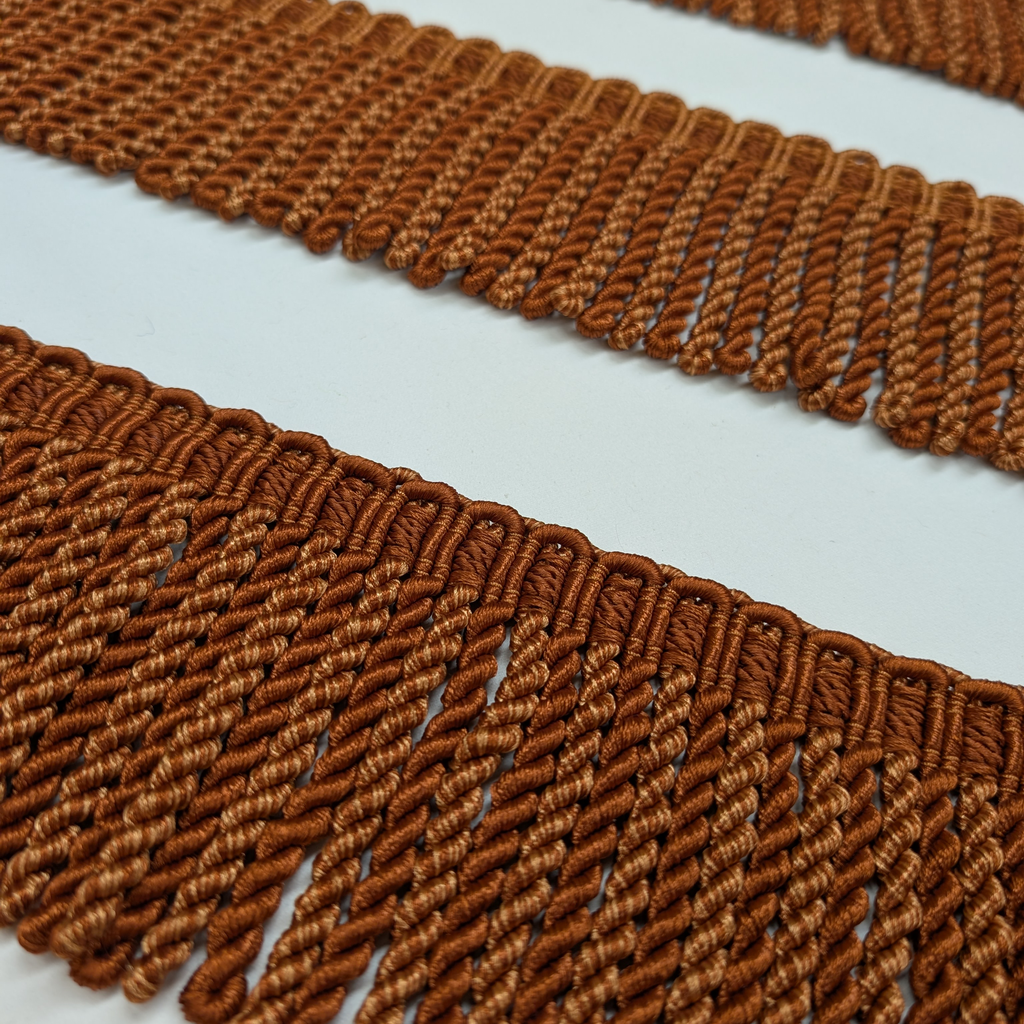 Close-up of brown woven fringes on a light gray background