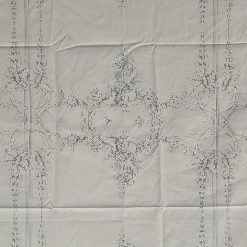 Decorative white fabric with intricate guilded patterns on a light gray background