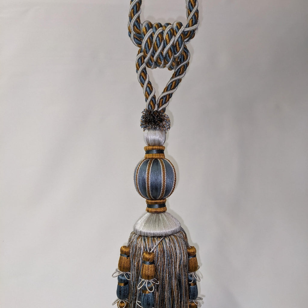 Decorative tassel with braided design and beads on a plain background