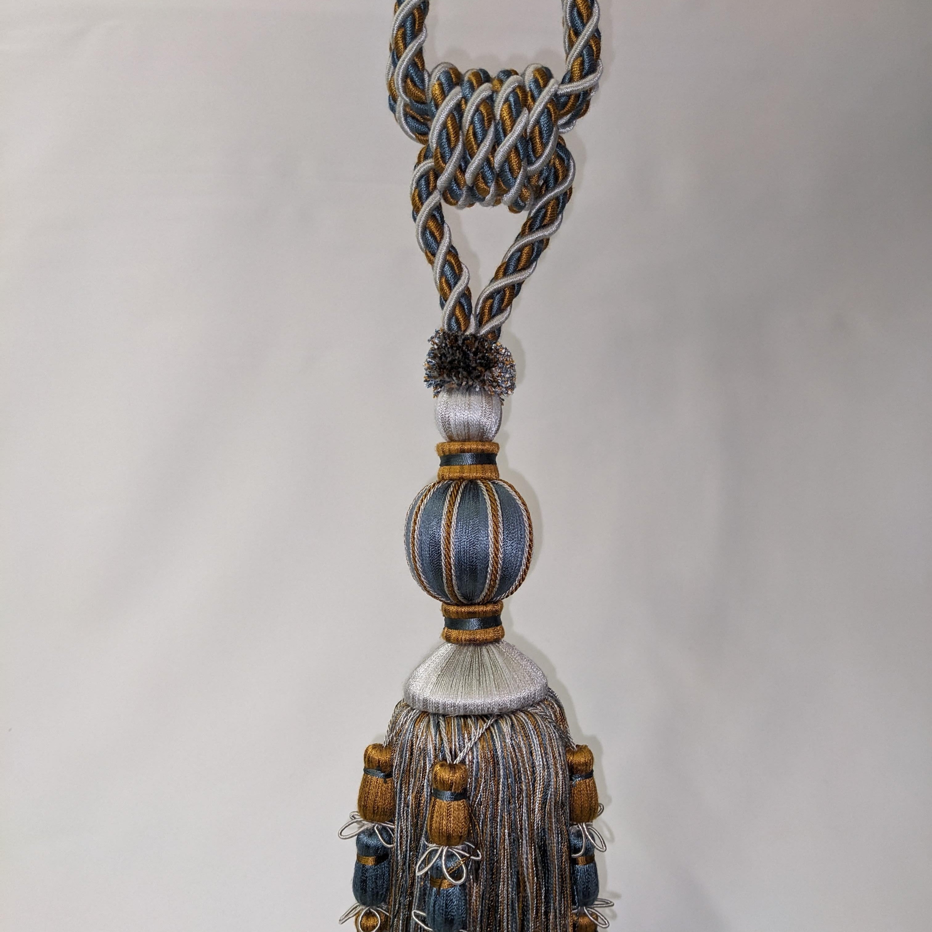 Decorative tassel with braided design and beads on a plain background