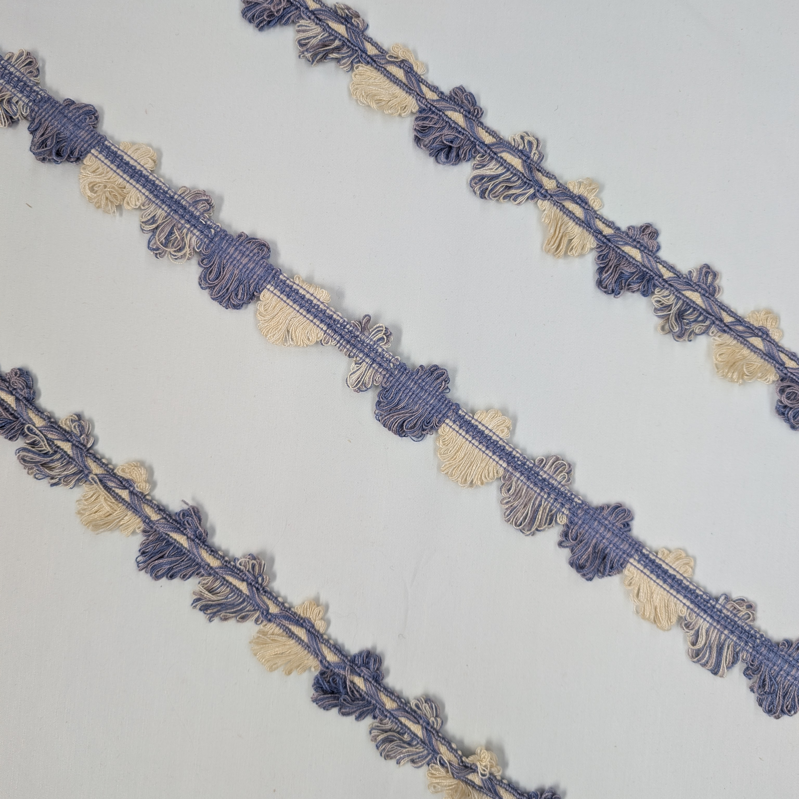 Decorative lace trim with blue and beige patterns on a white background
