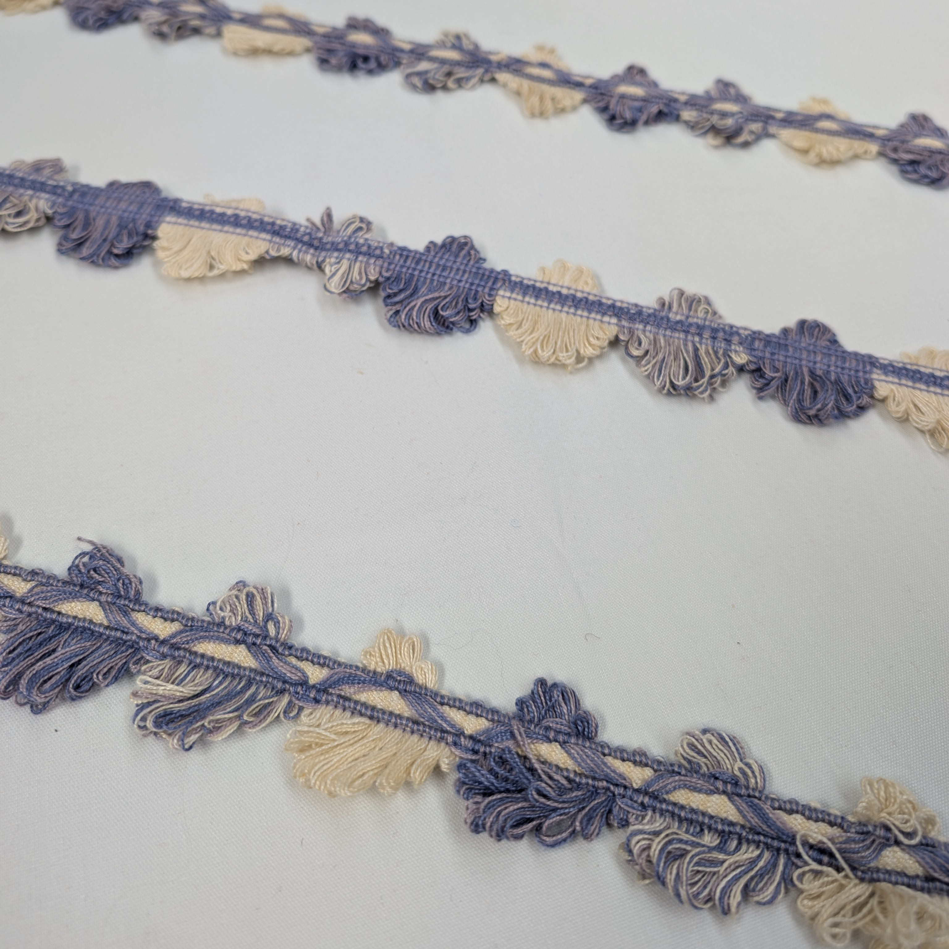 Decorative trim with blue and beige tassels on a white background