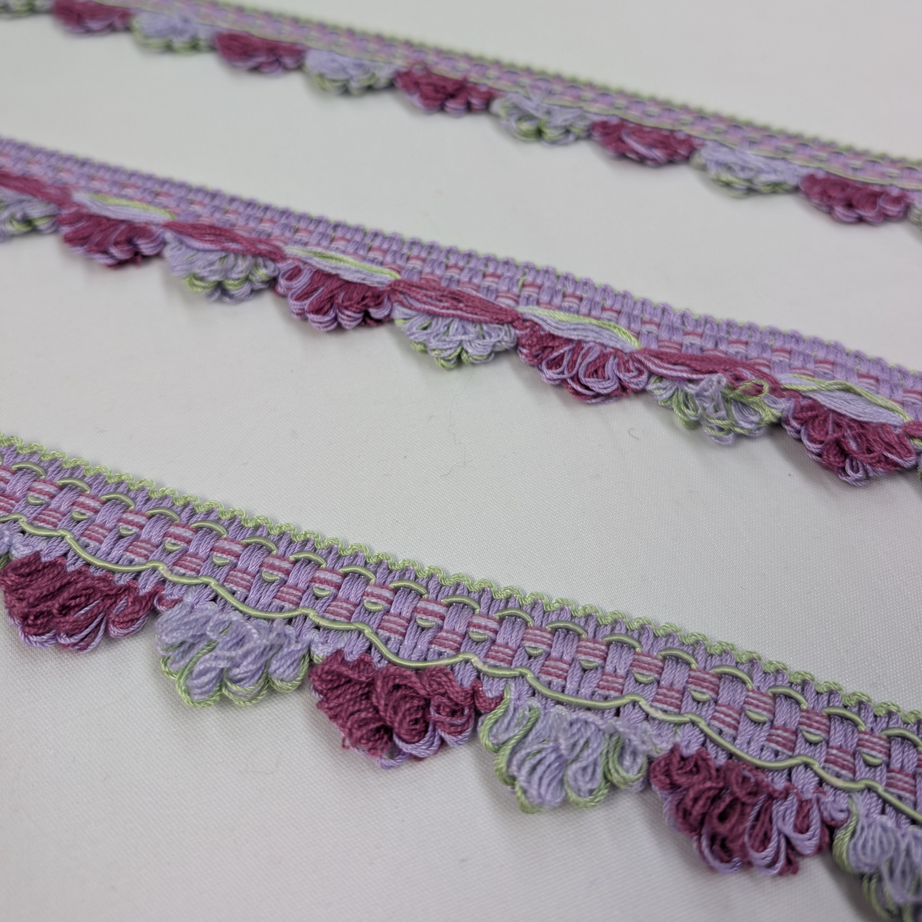 Decorative lace trim with pink and purple floral patterns on a white background