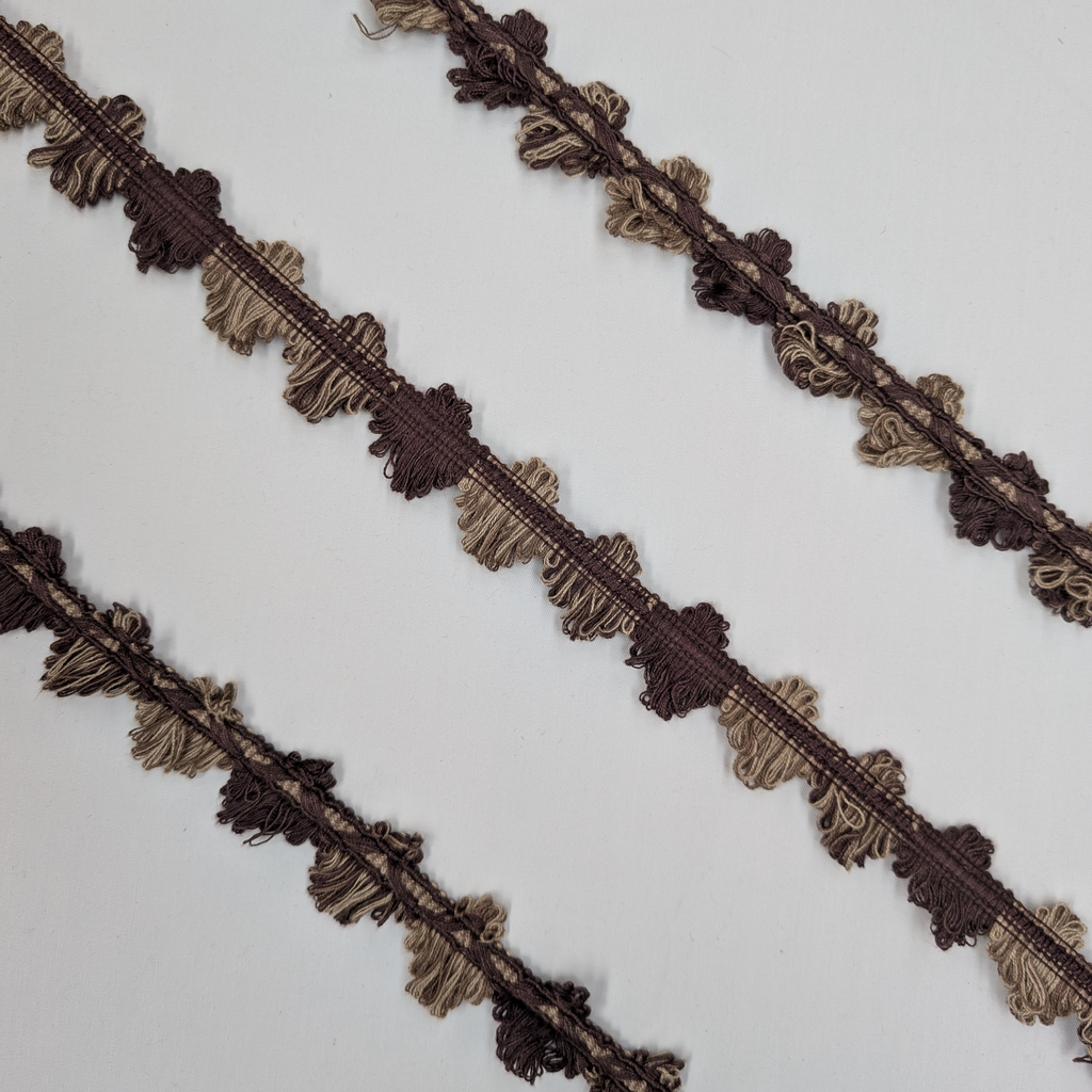 Decorative lace trim in brown and gold on a white background
