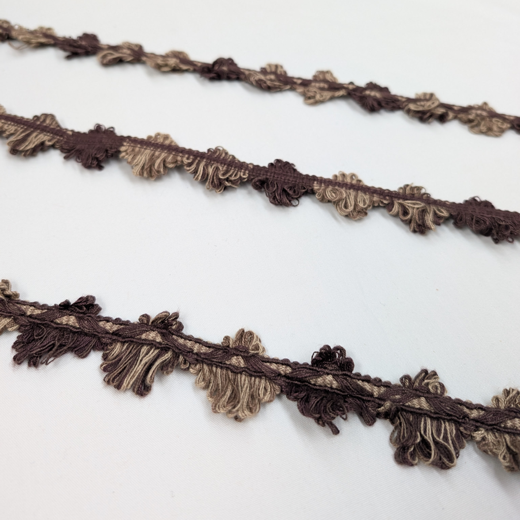 Two brown decorative ribbons with fringe on a white background