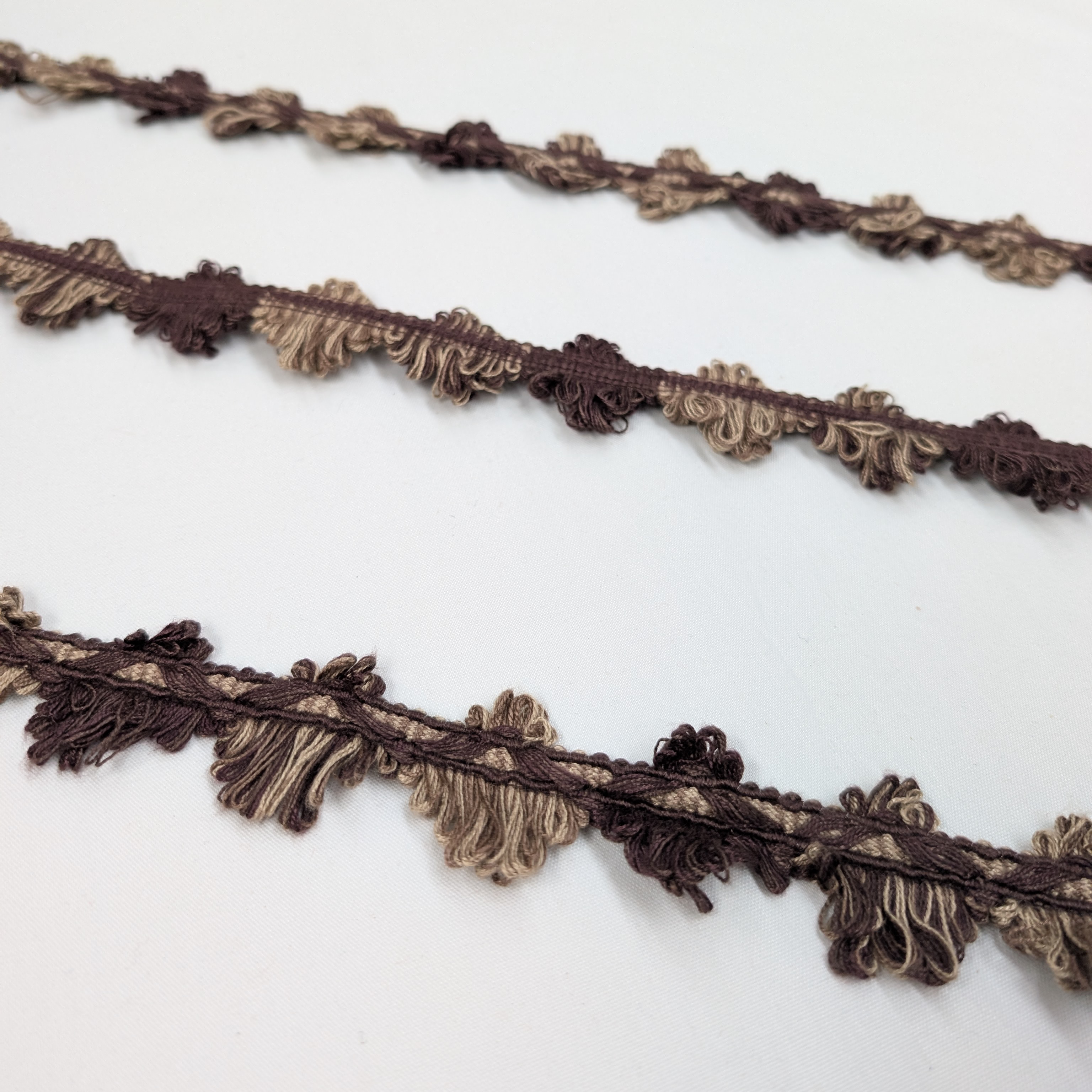 Two brown decorative ribbons with fringe on a white background