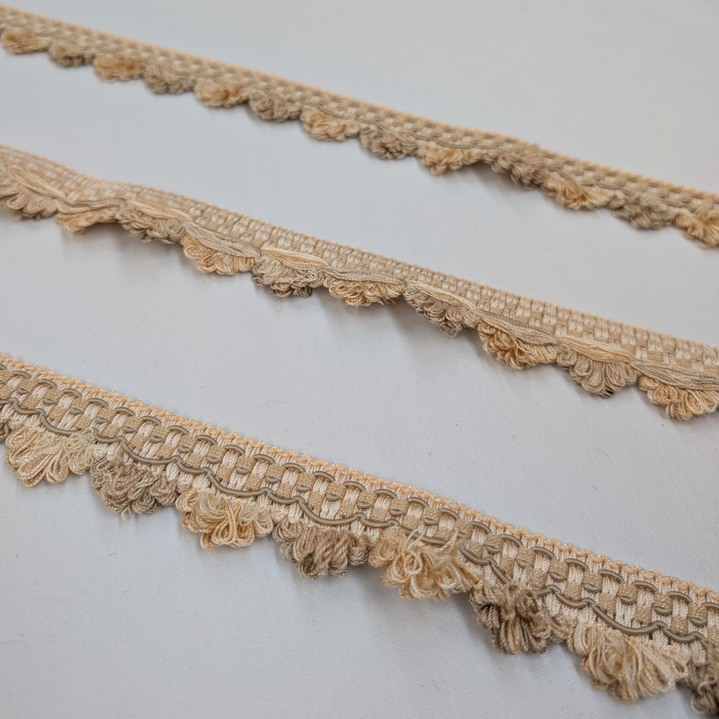 Three strips of beige lace trim on a light gray background