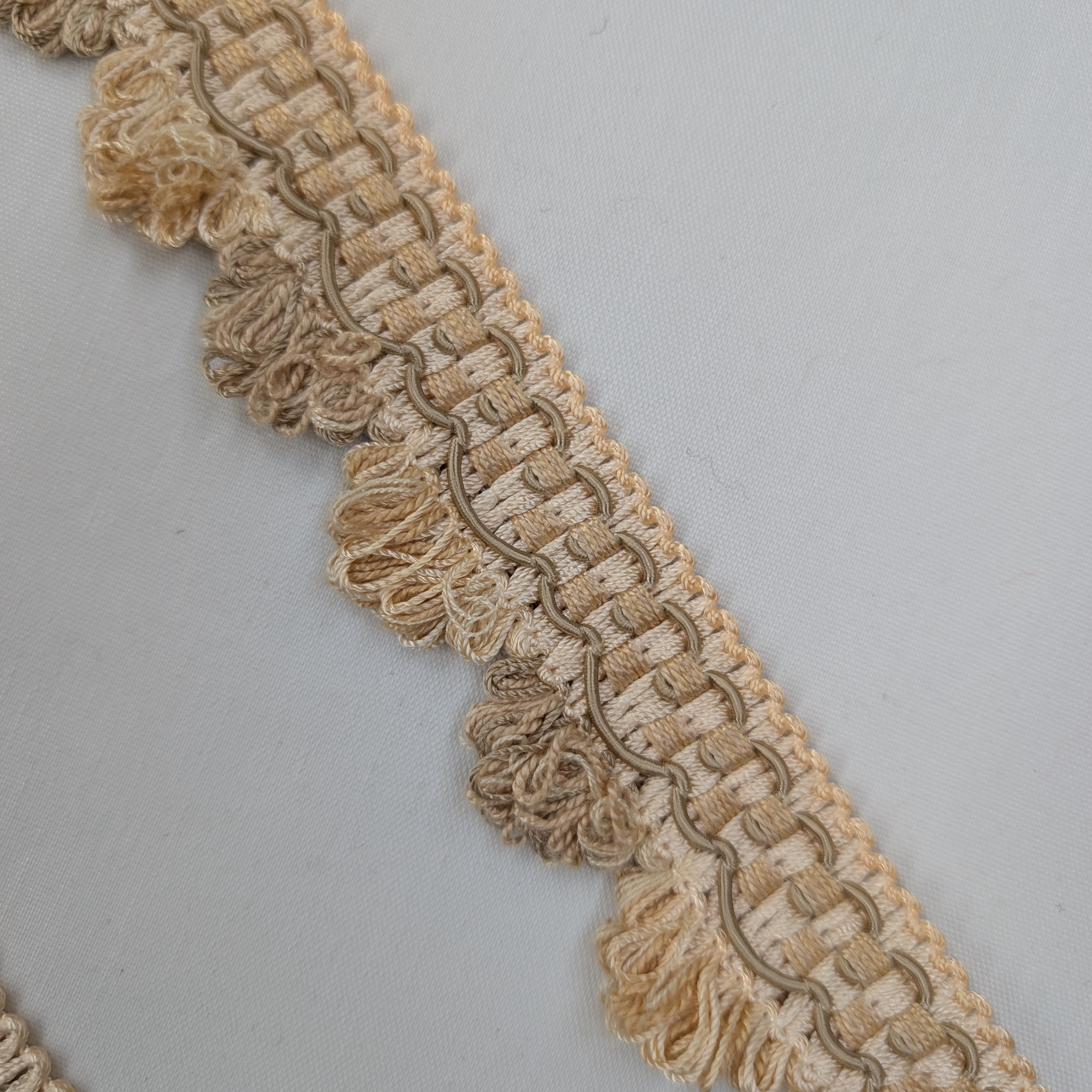 Close-up of beige lace trim on a gray background
