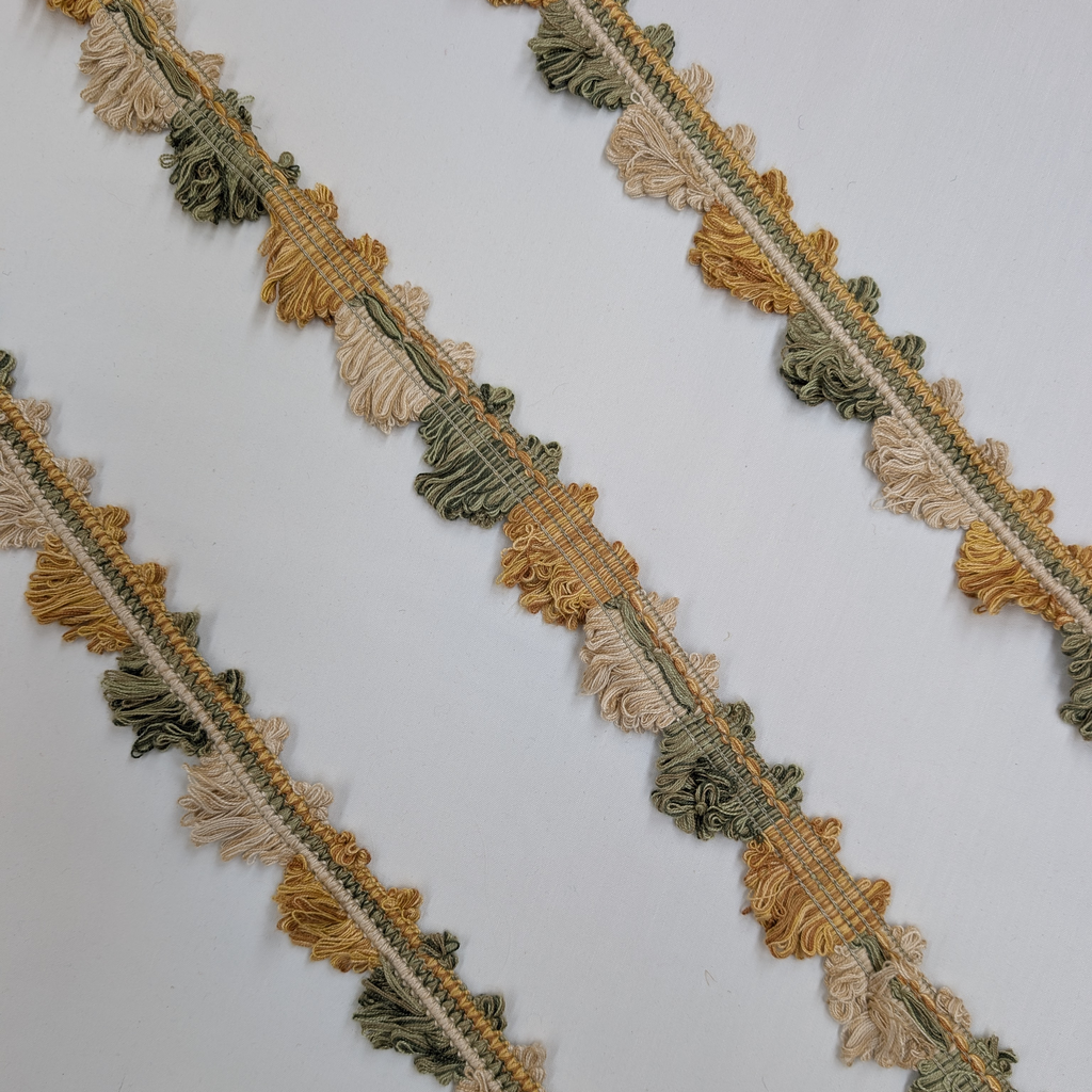 Decorative fabric trim with gold and green tassels on a white background
