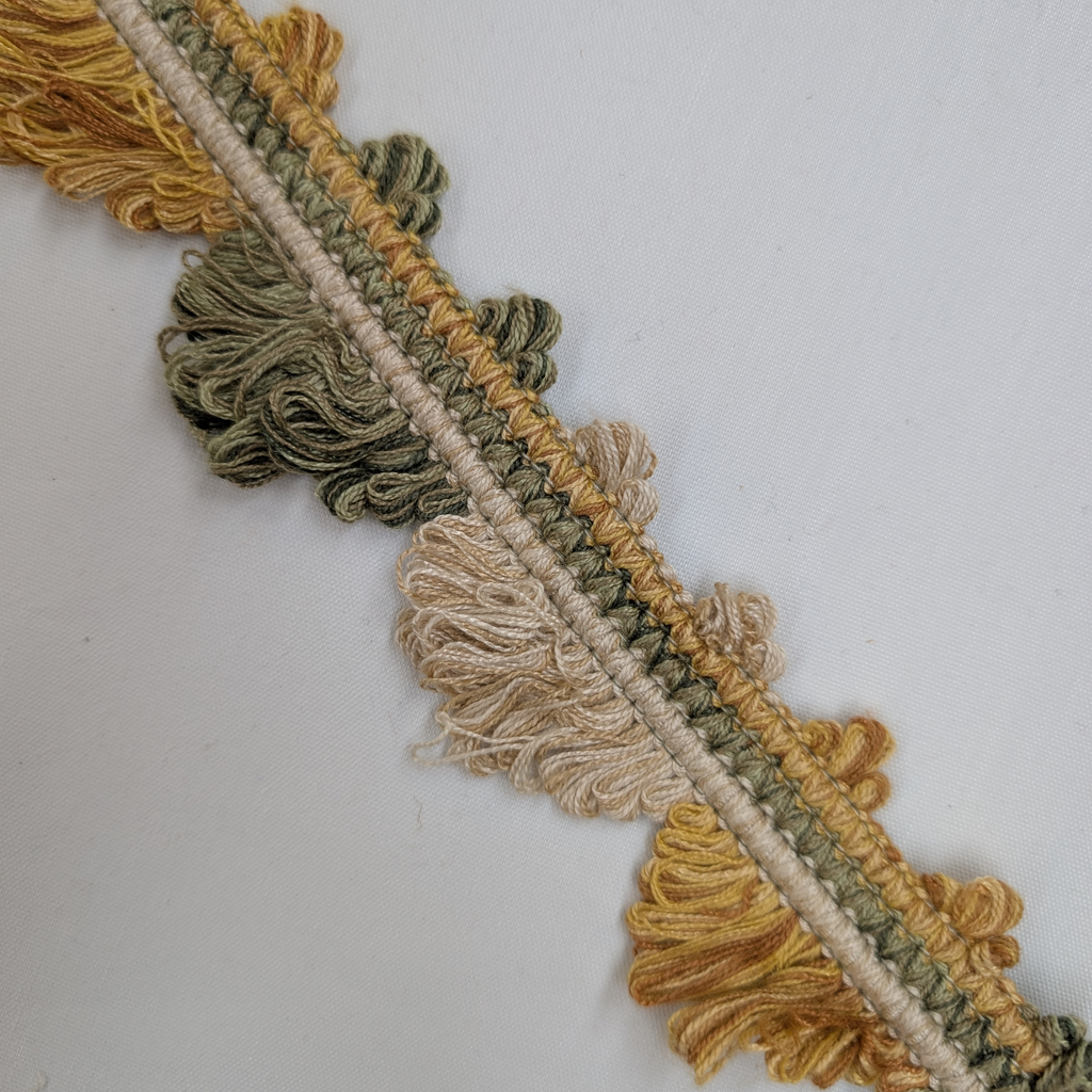 Close-up of a decorative trim with yellow, green, and beige colors on a white background.