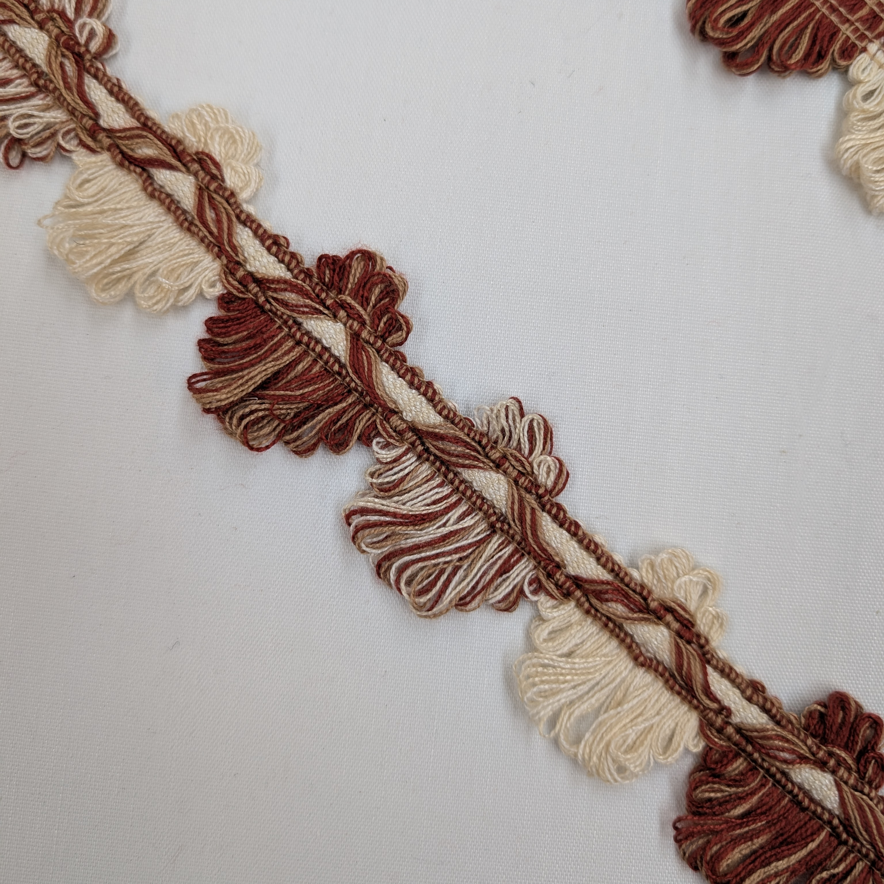 Decorative trim with brown and beige tassels on a white background