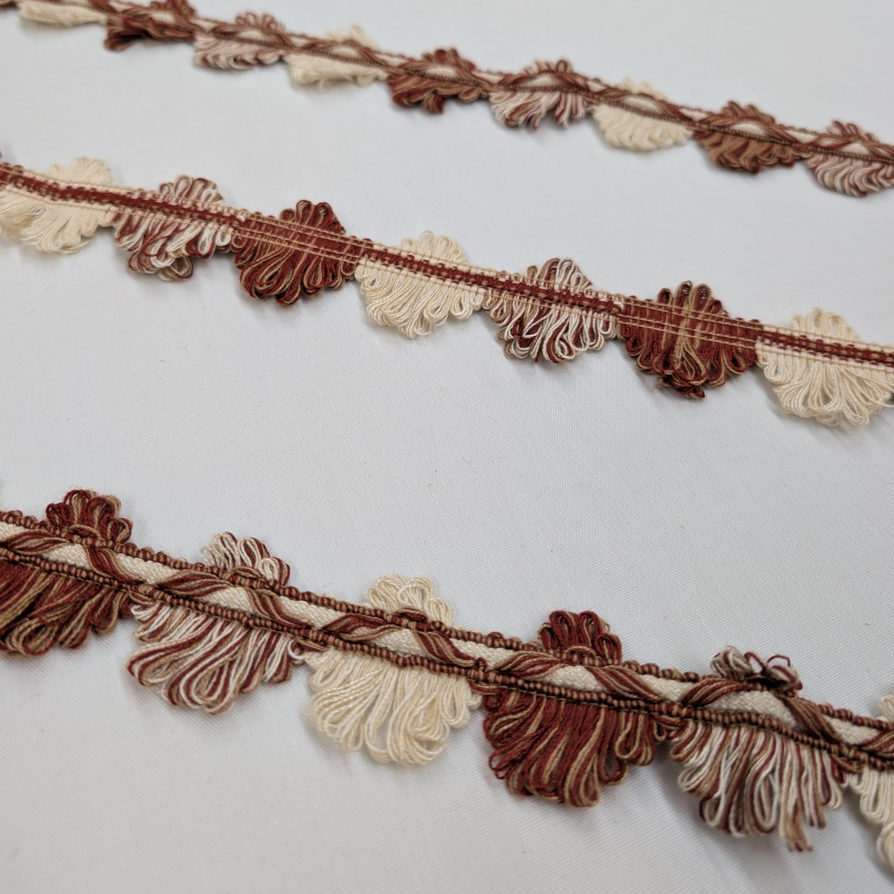 Decorative trim with brown and beige tassels on a white background