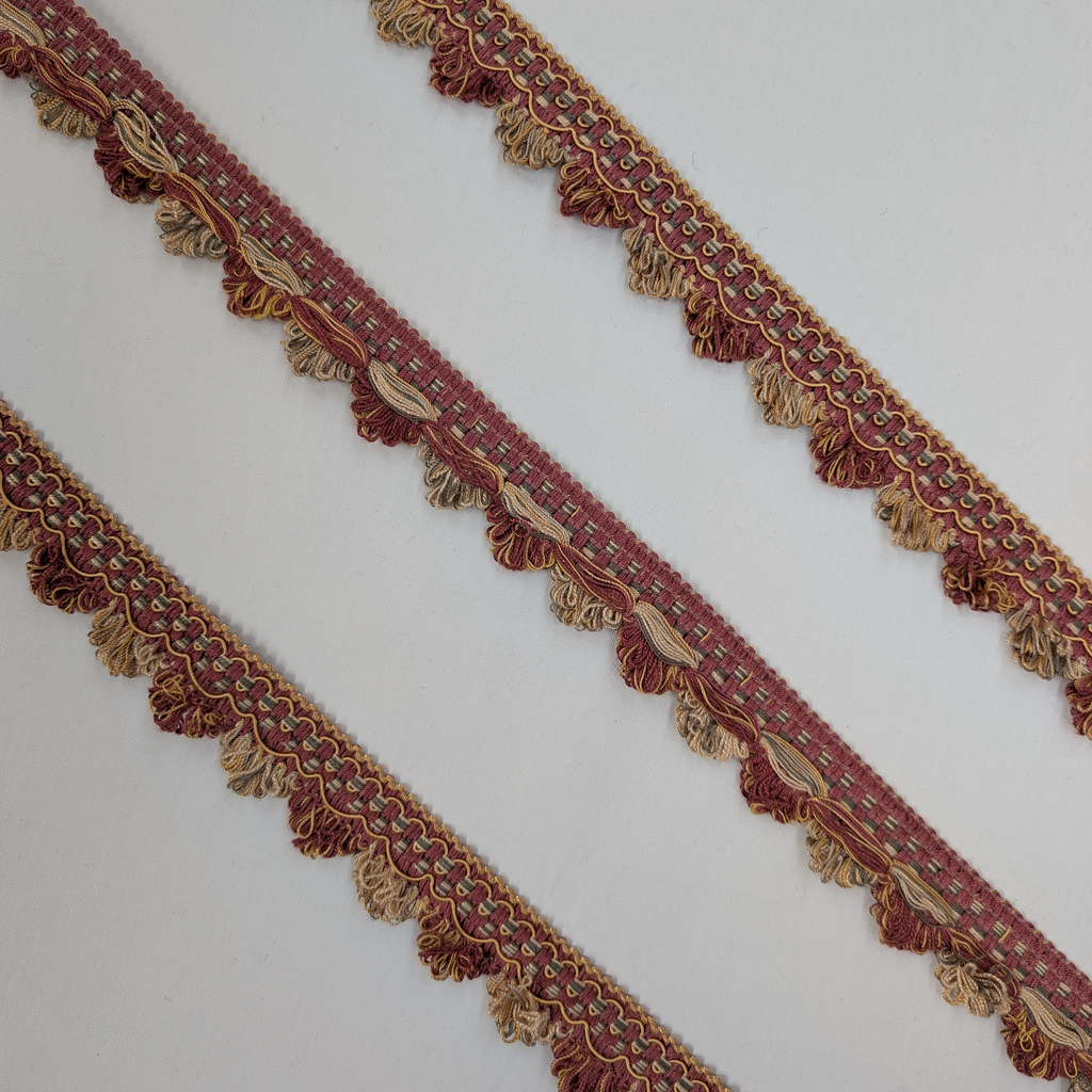 Decorative fabric trim with intricate patterns and tassels on a white background