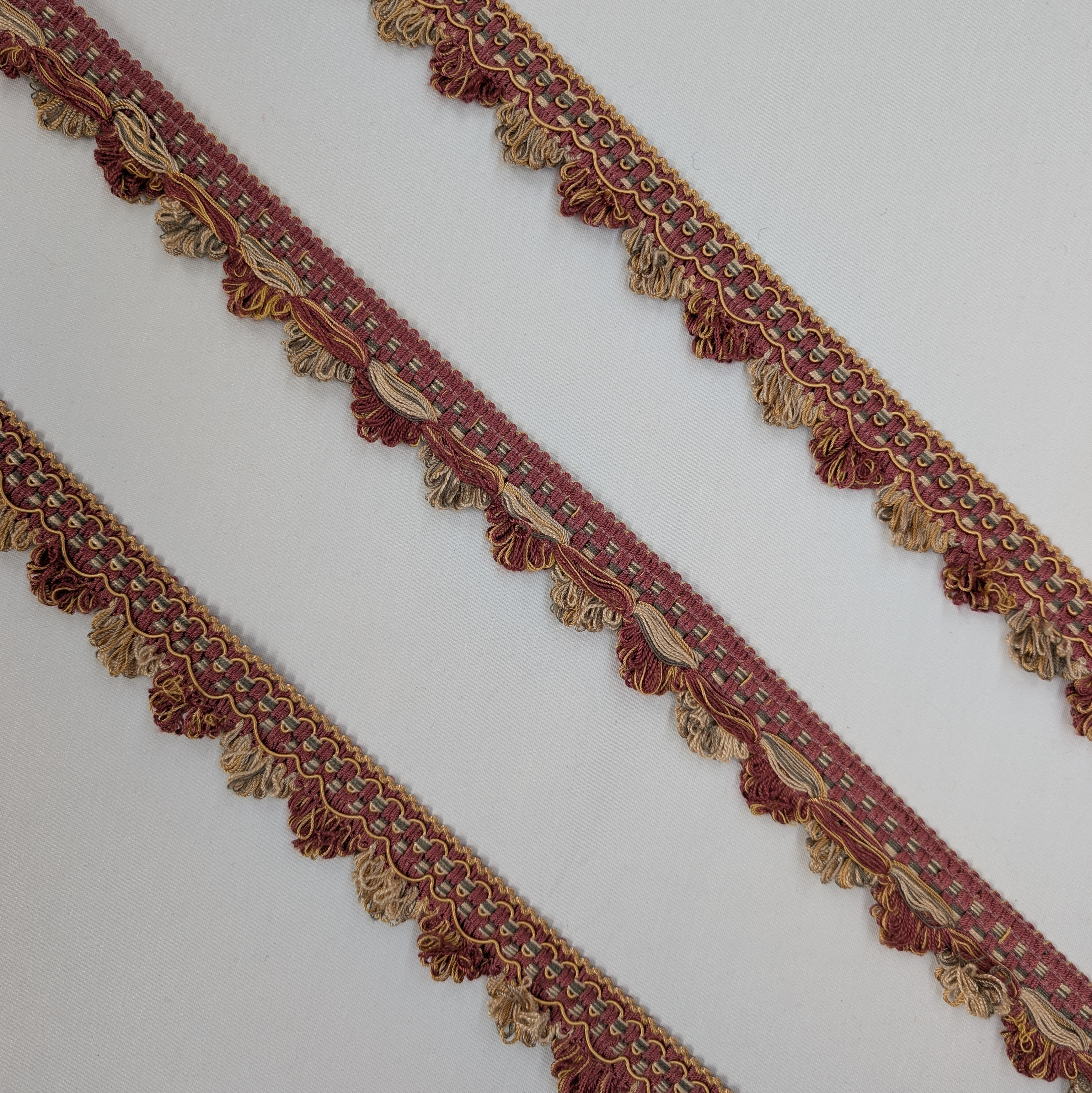 Decorative fabric trim with intricate patterns and tassels on a white background