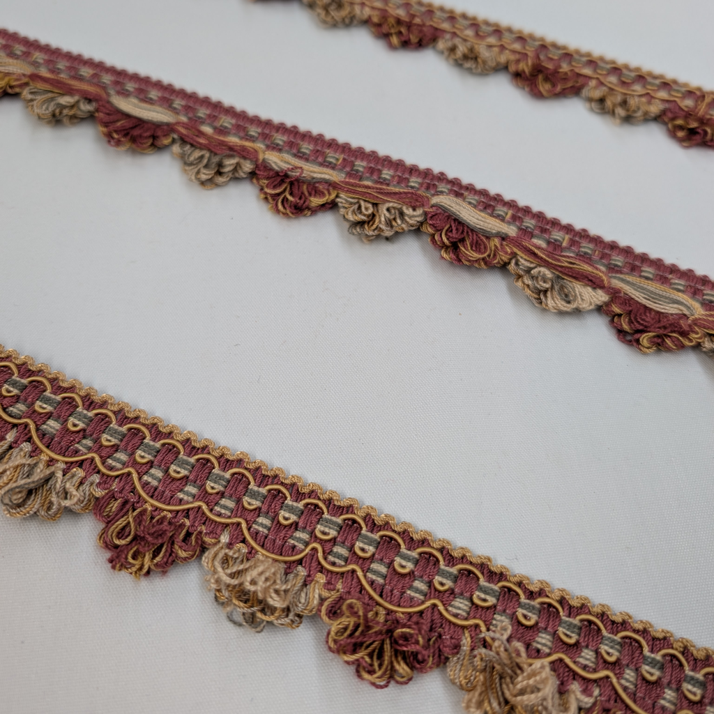 Decorative fabric trim with gold and red patterns on a white background