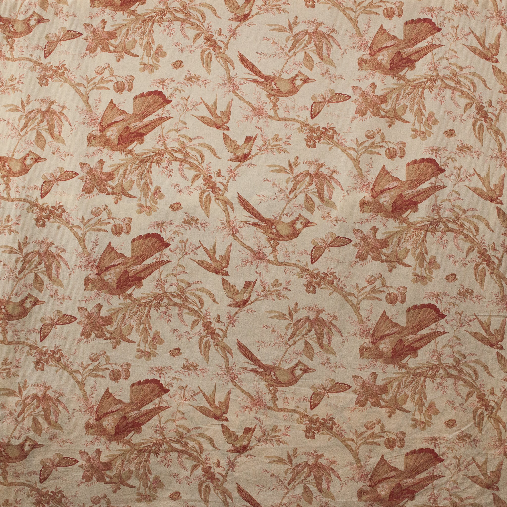 Patterned fabric with birds and floral designs in red on a beige background