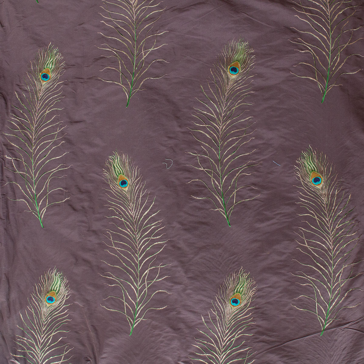 Pattern of peacock feathers on a textured purple fabric background