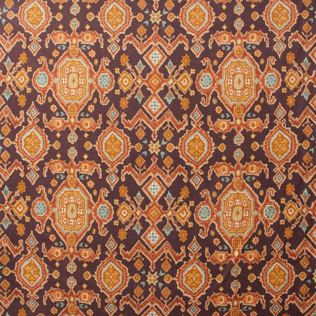 Patterned fabric with Moroccan design in orange, blue, and brown on a dark background