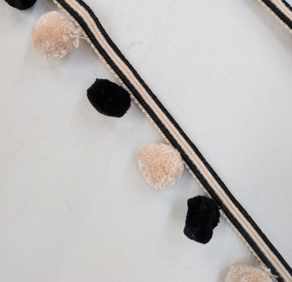 Pom-pom garland with black and beige pom-poms on a white background