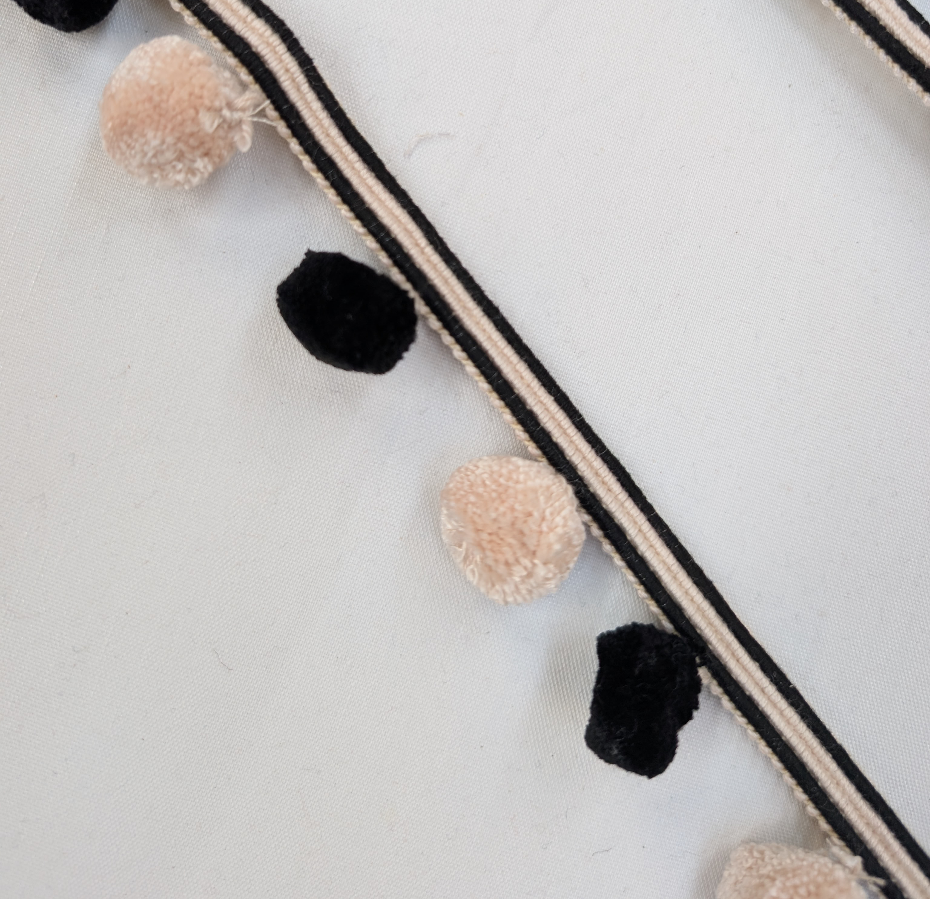 Pom-pom garland with black and beige pom-poms on a white background
