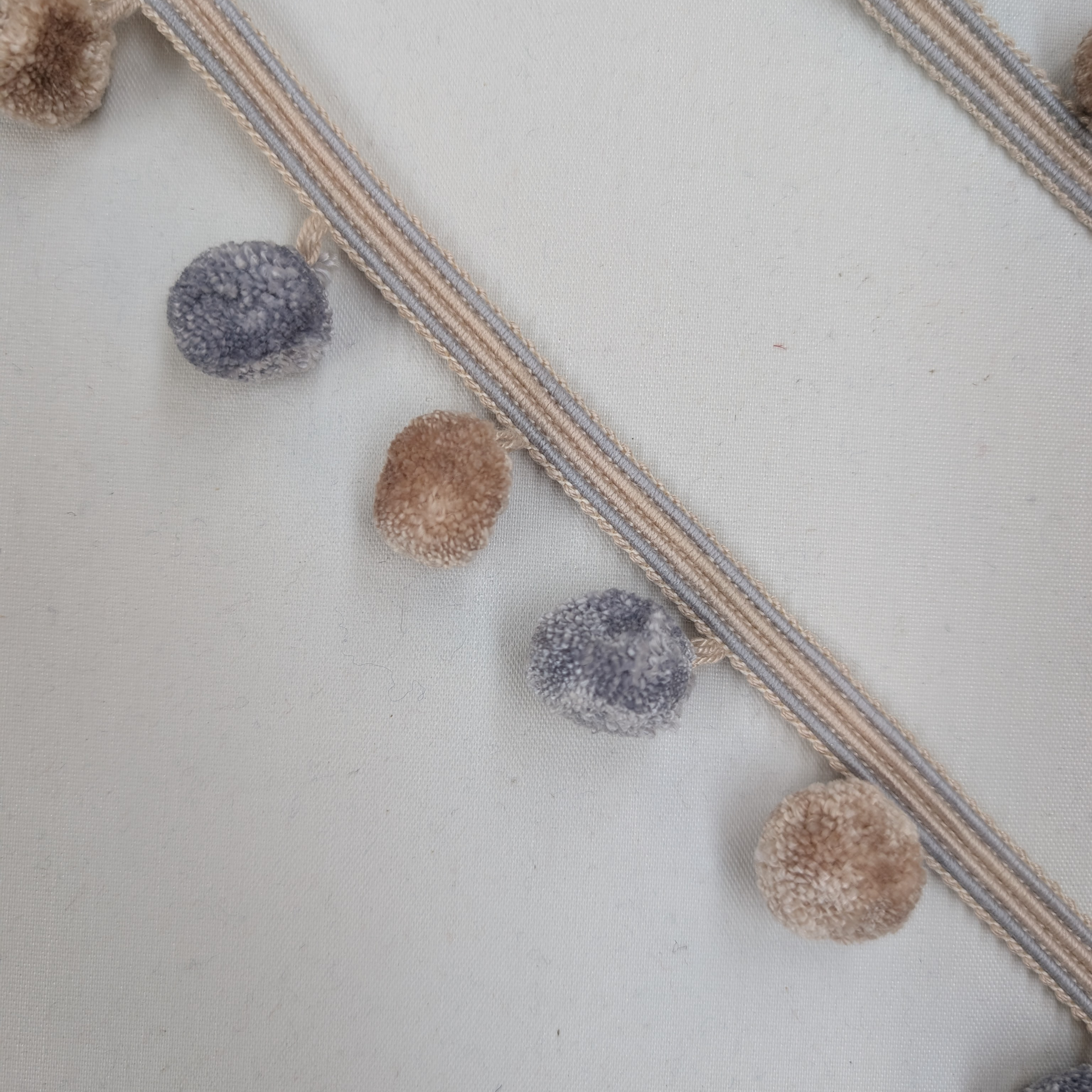 Decorative garland with pom-poms on a textured surface