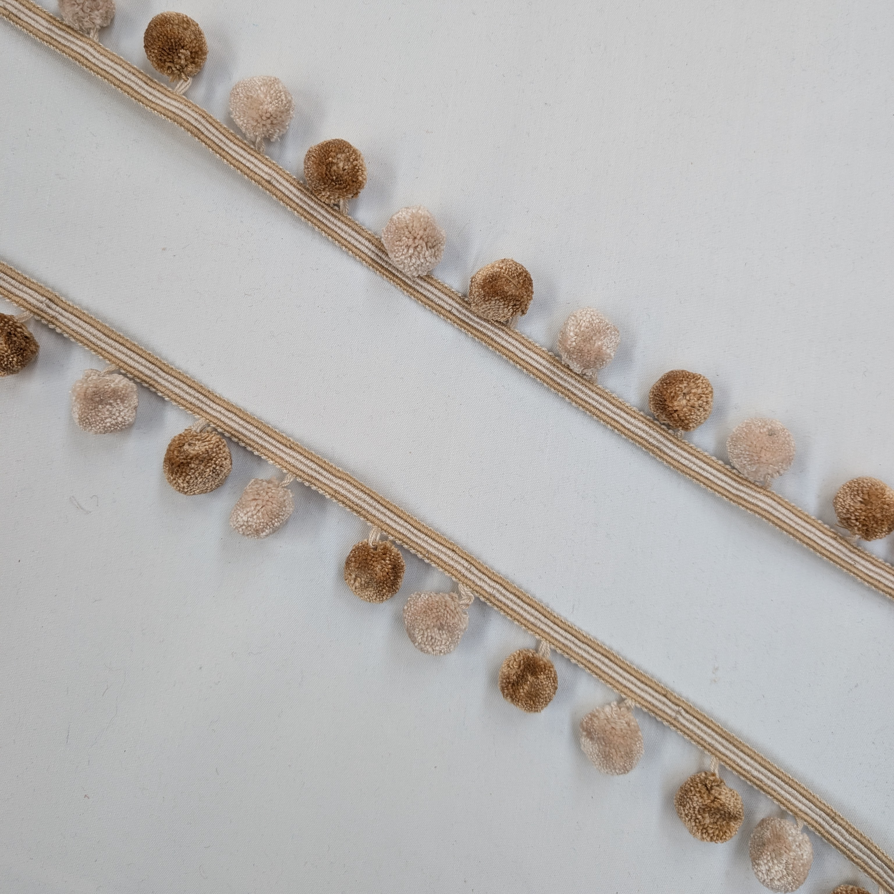 Decorative trim with Gold and beige pom-poms on a white background