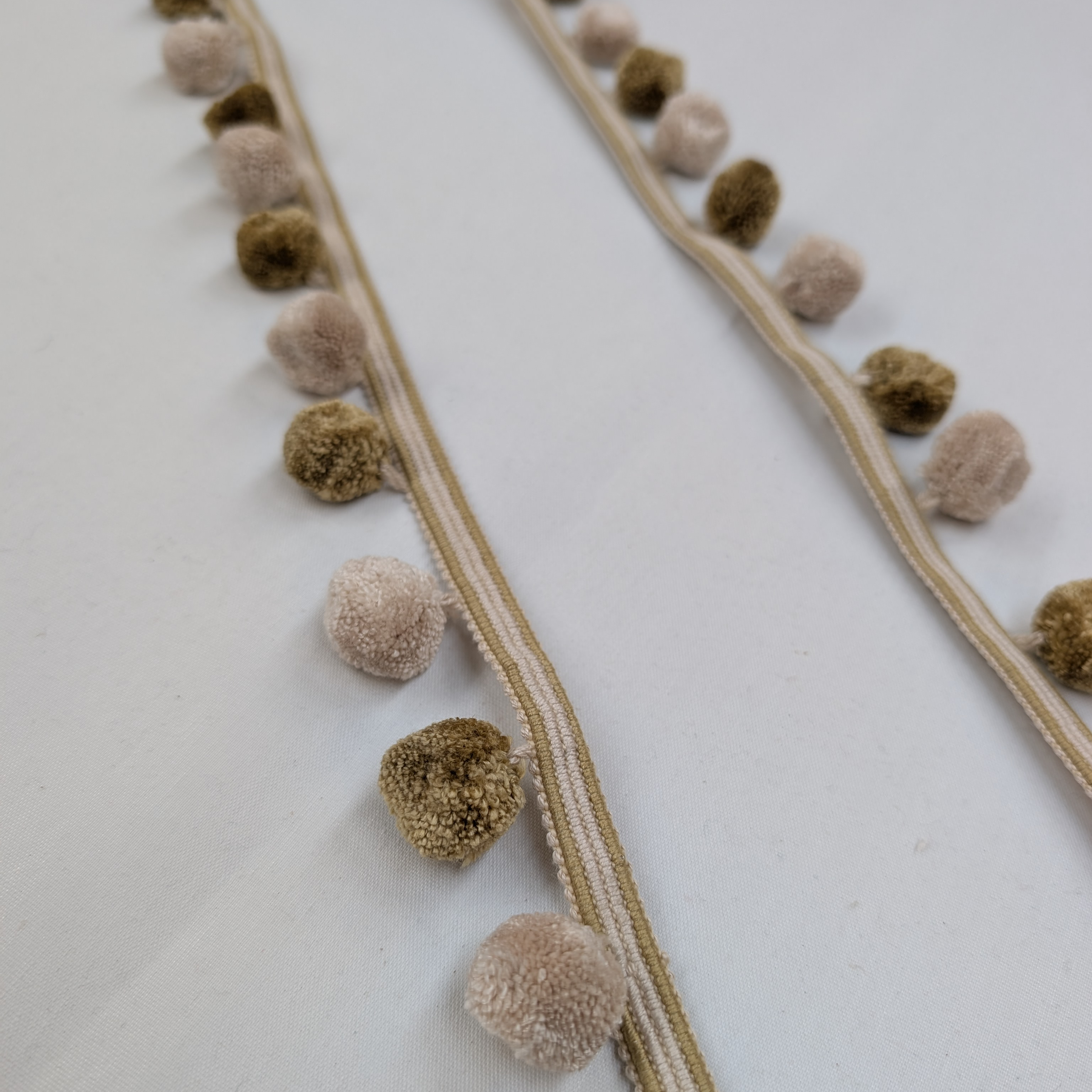 Decorative garland with brown and beige pom-poms on a white background