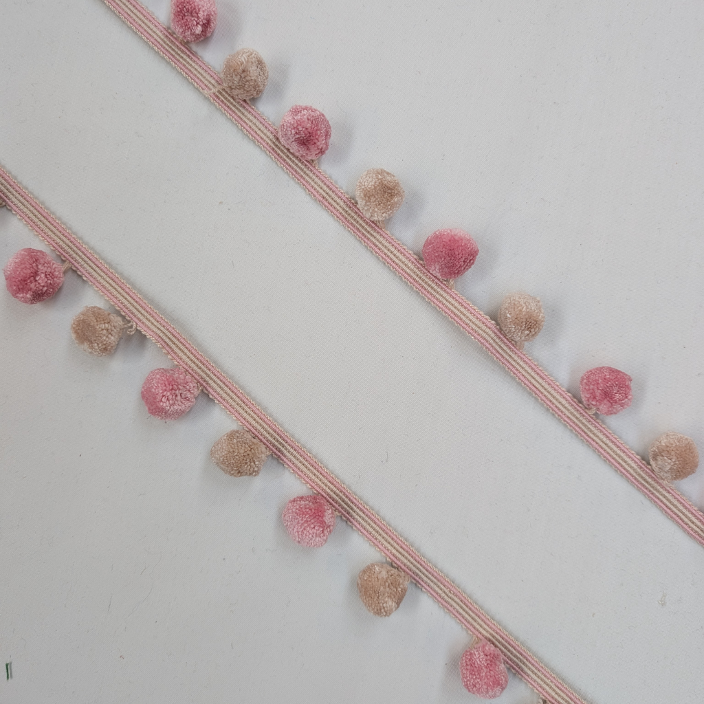 Decorative trim with pink and beige pom-poms on a white background