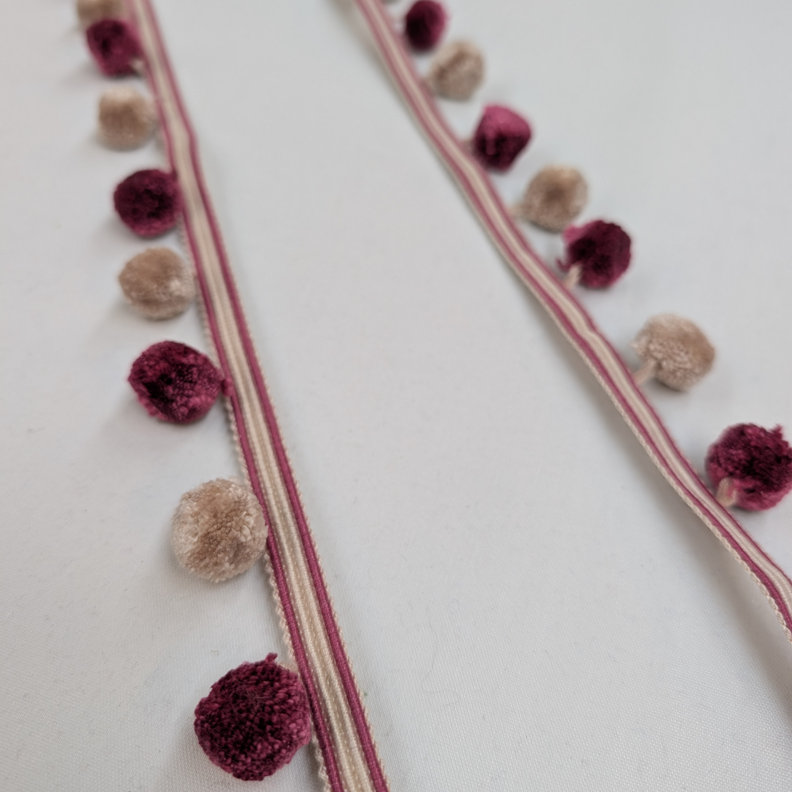 Decorative ribbon with maroon and beige pom-poms on a white background