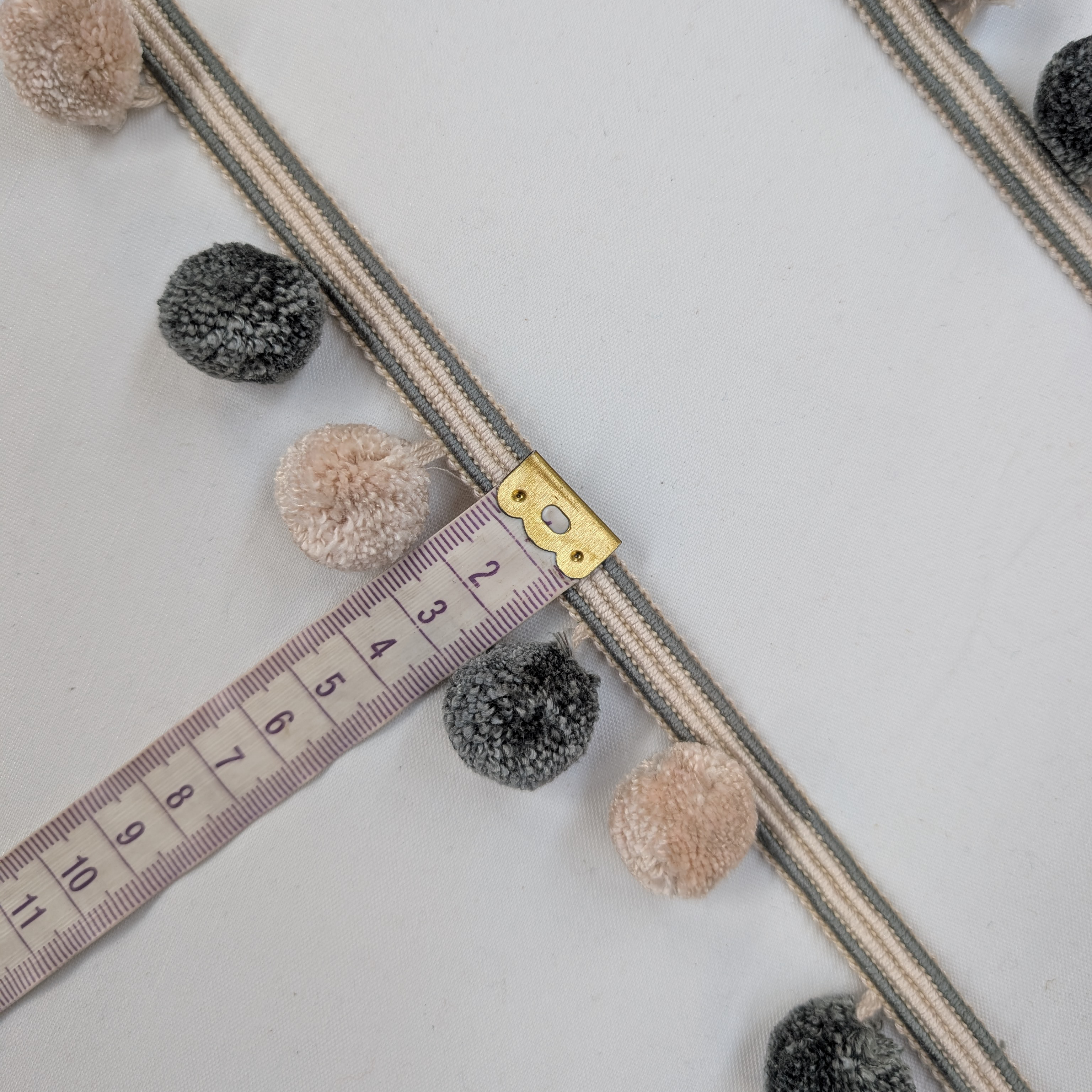 Pom-pom trim with a measuring tape on a light background