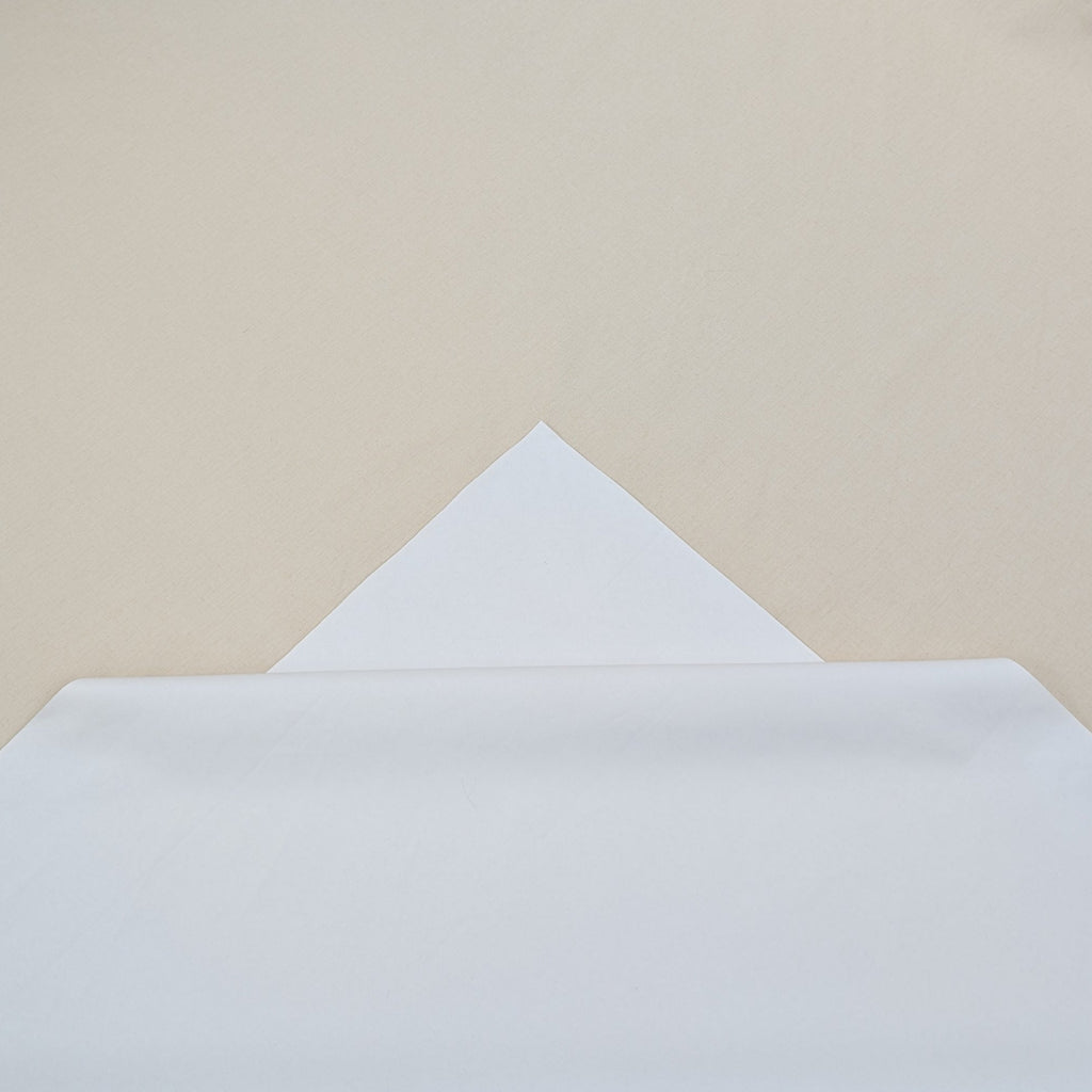 White paper on a wooden floor with a beige wall in the background