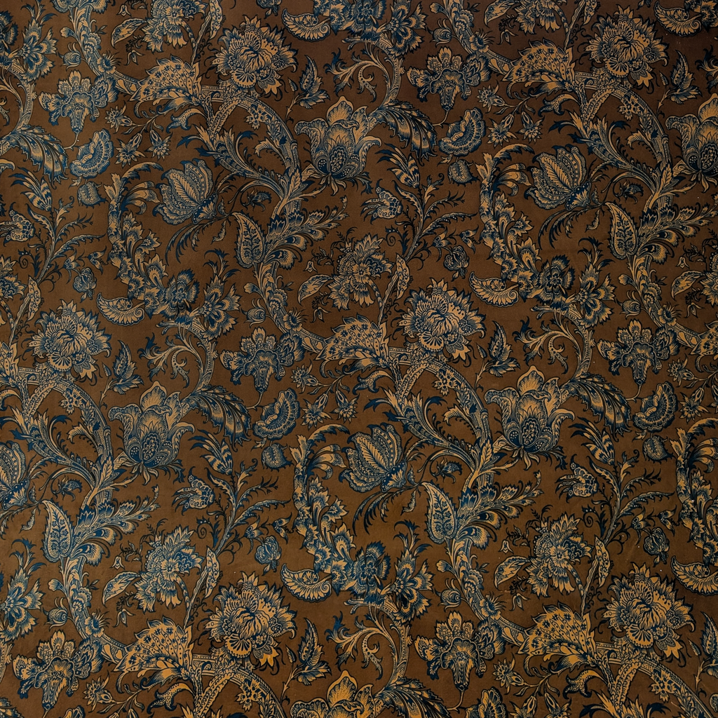 Decorative Jacobean fabric with blue floral and paisley pattern on a brown background