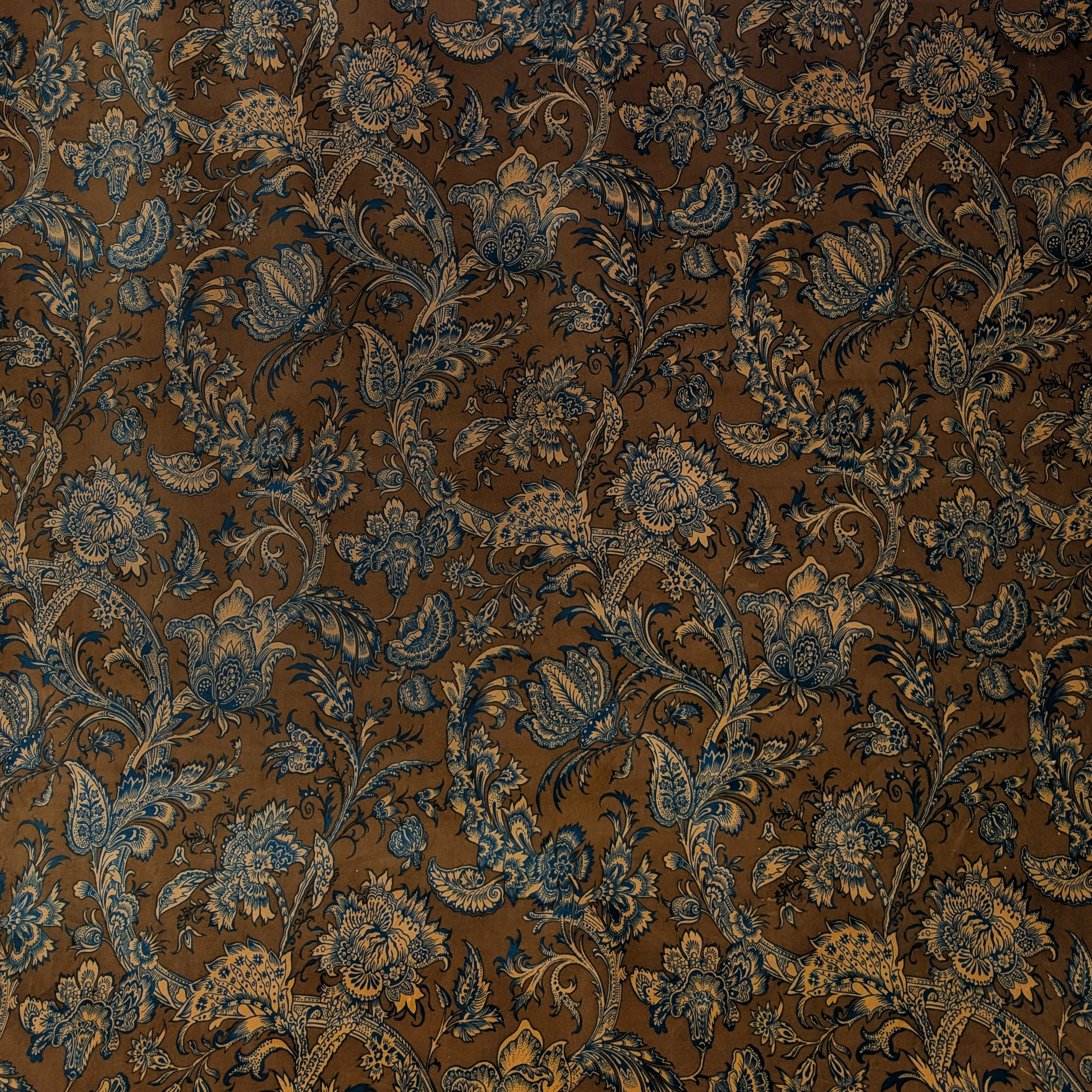 Decorative Jacobean fabric with blue floral and paisley pattern on a brown background